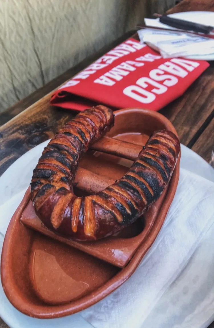 Chorizo flaming in a clay dish on a Vasco’s placemat