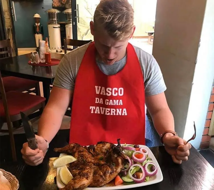 A guest in a Vasco da Gama Taverna apron about to start on a peri peri chicken