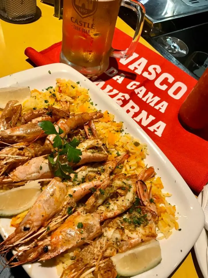Grilled prawns on rice beside a Vasco da Gama Taverna placemat