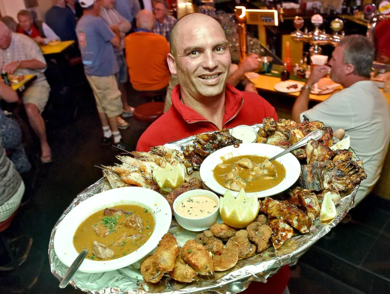 A waiter carrying a seafood platter through a full room